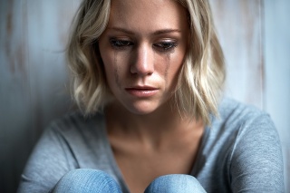 A young woman looking down while tears run down her face