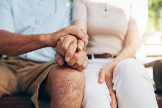 Close up shot of senior couple holding hand. Loving couple sitting together and holding hands. Focus on hands.