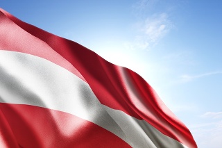 Flag of Austria waving in the wind. Blue sunny sky in the background. Horizontal orientation.