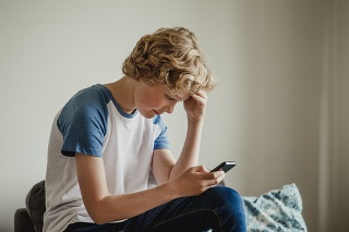 A teenage boy uses his phone to message his friends.