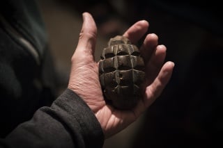 An old, defused grenade held in the palm of a hand in Nagorno-Karabakh. Concept shot for violence, time, fragility