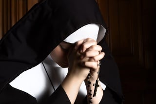 Fine art portrait of a novice nun in deep prayer with rosary