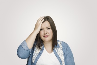 Depressed woman scratching head over grey background