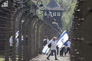 Ľudia s izraelskými vlajkami kráčajú počas návštevy bývalého koncentračného tábora Auschwitz pred Pochodom živých.