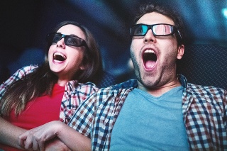 Closeup of mid 20's couple screaming while wathcing a movie at movie theater. Both wearing 3-d glasses and keeping their mouth open. She grabbed his hand. Low angle shot, toned image.
