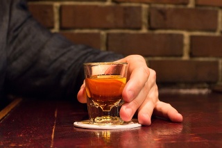 man holding a shot of golden whiskey
