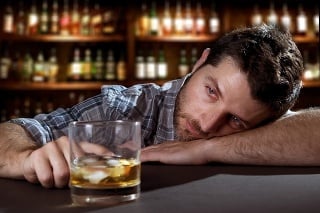 young alcoholic drunk man thinking wasted and sick about alcohol addiction indoors at bar of an irish pub looking whiskey glass trying to avoid drinking in alcoholism concept