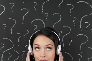 Attractive woman listening to music with question marks on a blackboard
