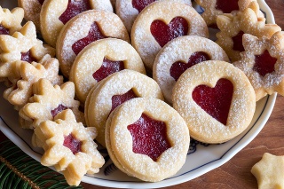 Linzer Christmas cookies filled with strawberry jam and dusted with sugar, arranged on a plate