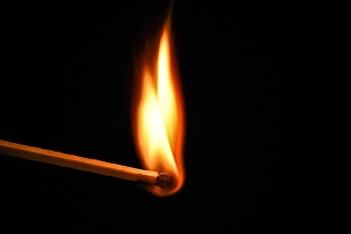 Fire burning on matchstick. Isolated on black background. Macro