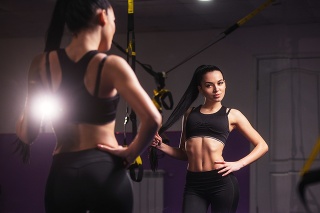 Sport, fitness, lifestyle concept. Beautiful woman in gym is looking at the mirror.