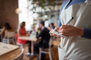 Close-up on a woman working at a restaurant as a waitress and holding a notepad