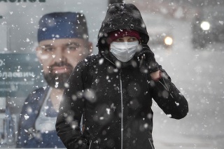 Žena s ochranným rúškom na tvári kráča počas hustého sneženia v Petrohrade.
