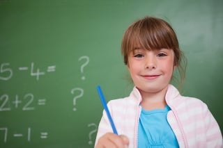 Cute girl holding a pen in front of a blackboard