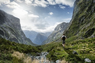 Tourist hiking amongst the beautiful landscape of the Southern Alps mountains in Fiordland National Park, New Zealand.