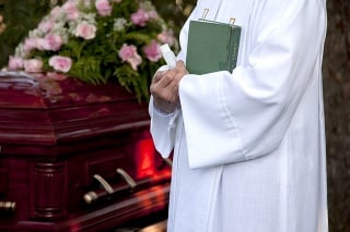 Shot of a priest standing near coffin