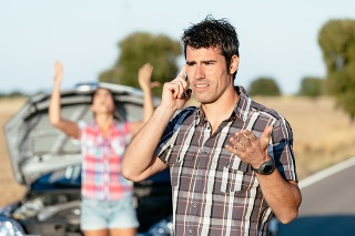 Man arguing on the cellphone with car insurance service. Upset couple in road trip problems because of breakdown engine.