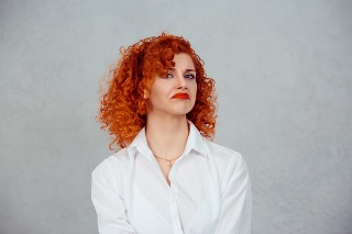 Confused woman. Closeup portrait unhappy young red head curly girl person shrugging shoulders I don't know concept on gray background. Negative human emotion facial expression reaction body language