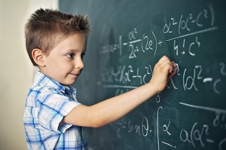 Cute little boy writing math formula. Looks like he's discovered something amazing and very important.
