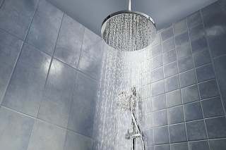 Low angle of running water from shower head in a cool coloured shower