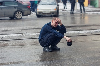 Nešťastný muž pred vyhoreným obchodným centrom.
