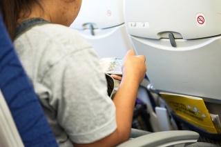 Asia lady passenger play games on mobile phone on plane during travel abroad on aircraft,technology concept