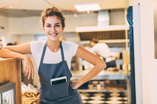 Beautiful young woman with digital tablet in the bakery, looking proud and confident
