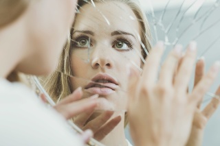 Face of schizophrenic woman reflected in broken mirror
