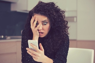 Young shocked anxious woman looking at phone seeing bad news photos message with scared emotion on face