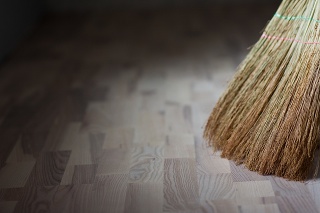 A broom stands on a wooden floor. Parquet board. New floor. Sweeping the floor. Broom