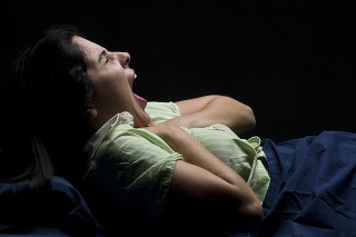 Hispanic woman with strong nausea at night on black background