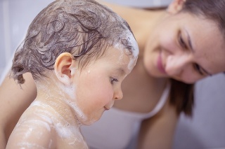 One child and mother, baby girl, mother care, taking a bath, covered in foam.