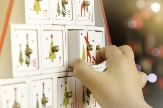 Child's hand pulling the last drawer (number 24) of a wooden advent calendar Christmas tree.