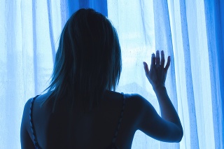 Lonesome girl holding a curtain.