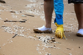 Dobrovoľníci odstraňujú z pobrežia kryštály stuhnutého palmového oleja.