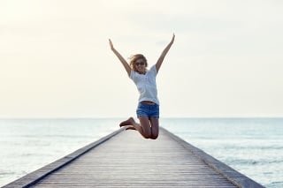 Happy jumping girl on the pier. Freedom concept