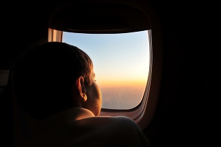 Kid watching sunset from airplane window seat.