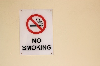 Sign on a wall with the words 'No Smoking' and a picture of a lit cigarette with a red cross through it indicating that smoking is not permitted in the area
