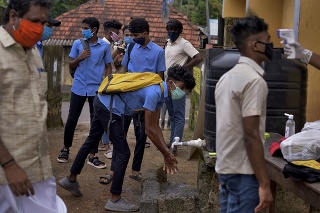 Študenti s ochrannými rúškami v rade na meranie teploty a dezinfekciu rúk v meste Koči.