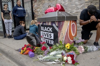 Ľudia sa modlia pri pamätníku  neďaleko miesta, kde polícia zatkla Afroameričana, ktorý neskôr zomrel.
