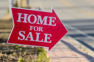A home for sale sign pointing directing people to a house for sale