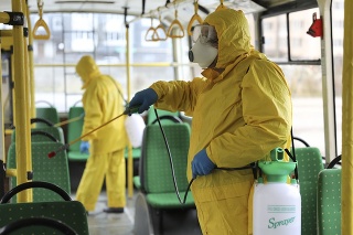 Zamestnanci v ochranných oblekoch dezinfikujú autobus na ochranu pred koronavírusom na Ukrajine v Ľvove. 