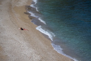 Dievča na na opustenej verejnej pláži na brehu Jadranského mora v chorvátskej Opatiji.