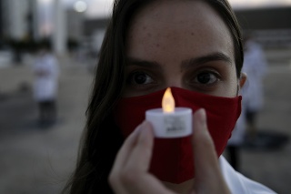 Zdravotná sestra drží umelú sviečku na pamiatku kolegu, ktorý zomrel počas boja proti novému koronavírusu.