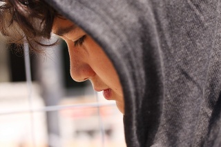 Sad troubled hispanic school boy teenager wearing a hoodie posing outdoor - close up stock photo