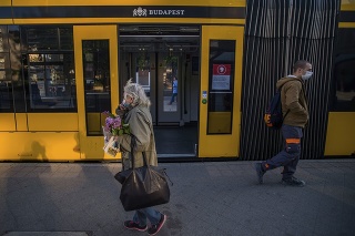Cestujúci s ochrannými rúškami na zastávke električiek na námestí Nyugati v Budapešti.