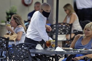  Čašník s ochranným rúškom na tvári pri obsluhovaní zákazníkov 4. mája na Floride.