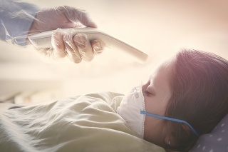 Doctor checking temperature of a sick girl laying in the bed