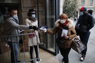 Dobrovoľníci rozdávajú ochranné rúška cestujúcim na vlakovej stanici Saint Lazare v Paríži.