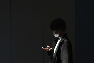 Žena s ochranným rúškom na tvári kráča cez prázdny podchod v Tokiu.